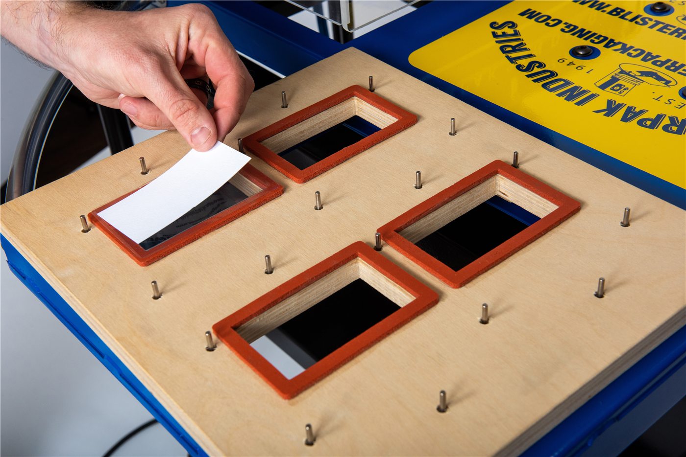 Wooden blister packaging tooling tray with product openings and locating pins